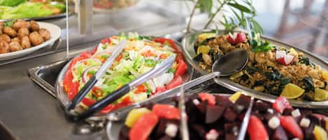 Ein reichhaltiges Buffet mit verschiedenen Speisen, darunter Salate, Früchte und Getreide.