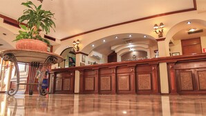 Eine Hotellobby mit einer Rezeption, einer großen Pflanze im Topf und einem polierten Boden.