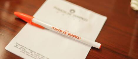 A white envelope with a red and white pen on top, placed on a wooden surface.