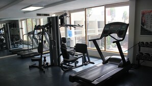 Ein Fitnessstudio mit Laufbändern, Kraftgeräten und Kurzhanteln.