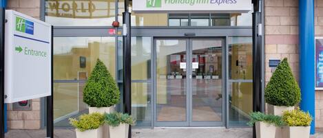 The entrance to a Holiday Inn Express hotel with a glass door and automatic doors.