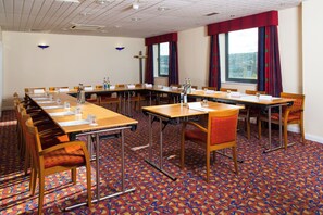 A conference room with a long table, chairs, and a patterned carpet.