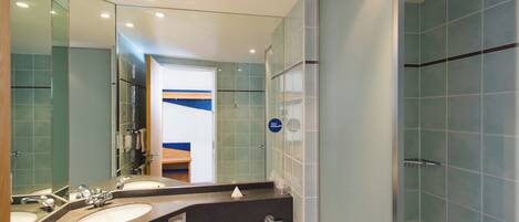 A modern bathroom with two sinks, a mirror, and a shower area.