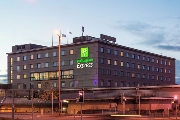 Un hotel Holiday Inn Express con un diseño moderno, que presenta un logotipo verde destacado y varias ventanas.
