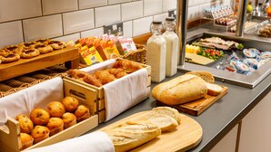 A breakfast buffet with muffins, croissants, bread, and various spreads.