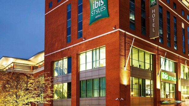 A hotel with a prominent 'ibis Styles Hotel' sign, large windows, and a modern architectural design.