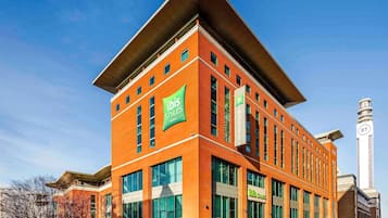 A modern hotel with a prominent 'ibis Styles' sign, large windows, and a tall tower with 'BT' branding.