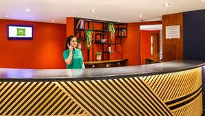 A reception desk with a modern design, a digital screen displaying 'ibis Styles', and a sign about the Hotel Proprietors Act.