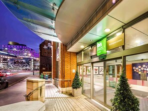 A hotel entrance with a green sign, a glass door, and a brick wall. - ibis Styles Birmingham Centre (Birmingham)