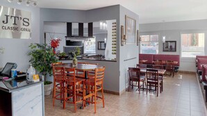A restaurant with a central dining area, a kitchen, and a seating area with red booths. - Quality Inn & Suites Edmonton International Airport (Leduc)