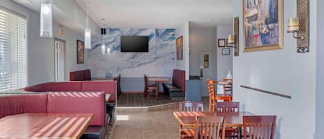 En restaurang med avskilda bås, bord och en tv-skärm som är monterad på väggen.