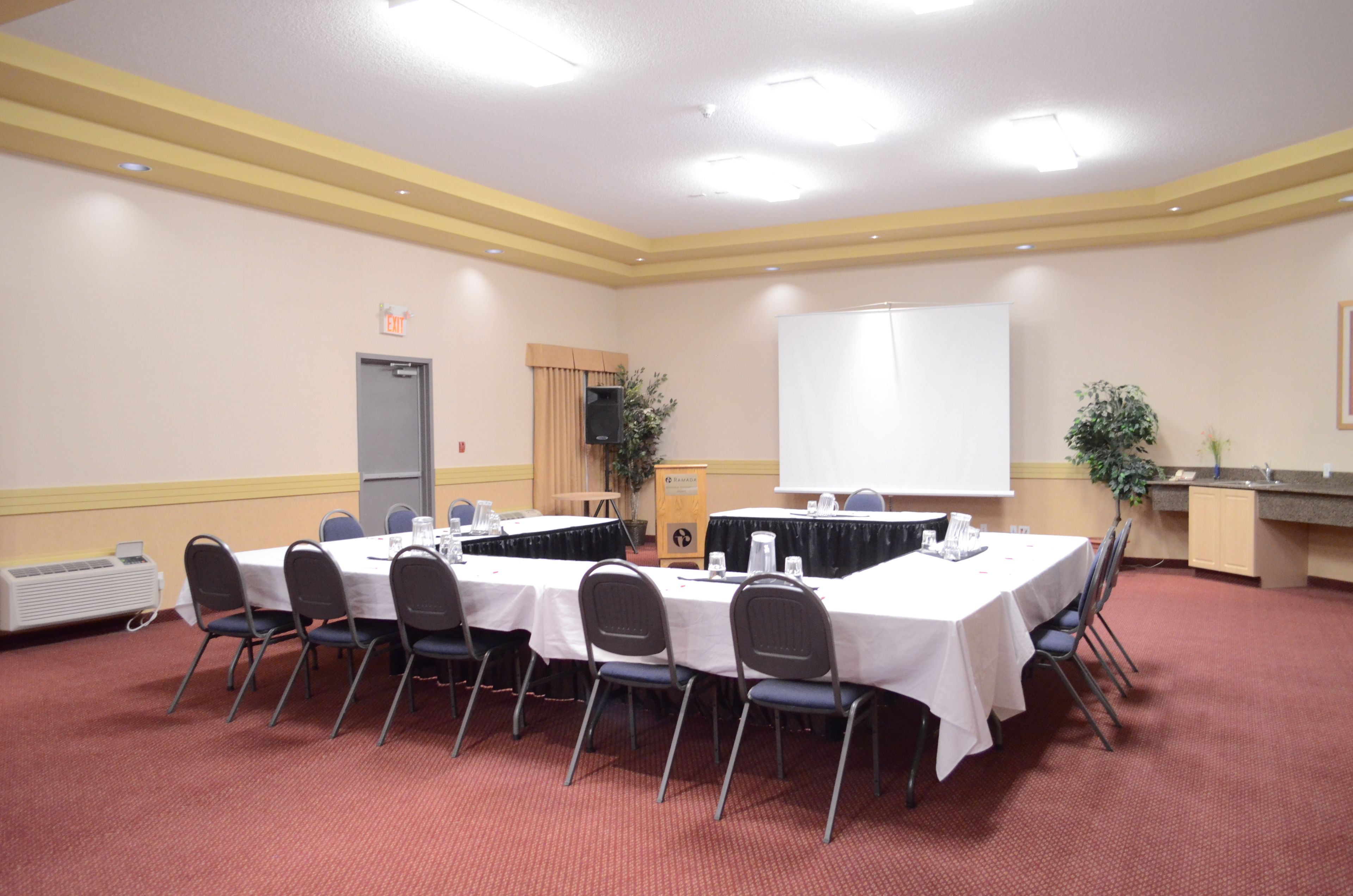 A conference room with a long table, chairs, a whiteboard, and a speaker.