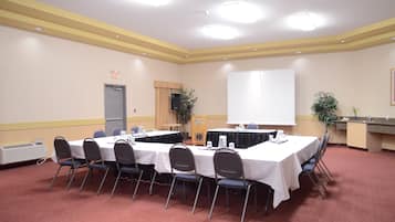 Une salle de conférence équipée d’une longue table, de chaises, d’un tableau blanc et d’un système audio.