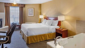 A hotel room with a bed, bedside lamps, a desk with a chair, a bathroom with a bathtub, and a window with curtains. - Quality Inn & Suites Edmonton International Airport (Leduc)