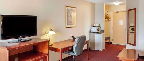 Habitación de hotel con televisión, escritorio, silla, cómoda y microondas.