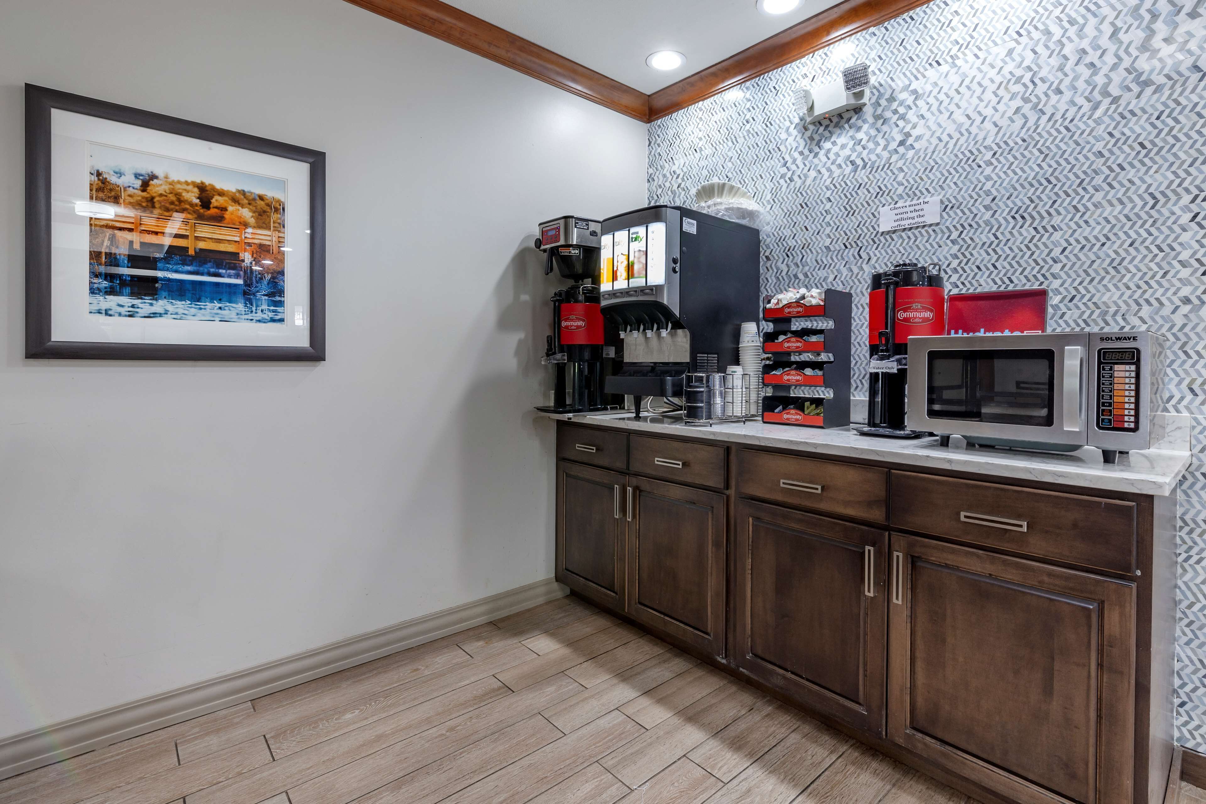 A kitchenette with a coffee machine, microwave, and storage cabinets.