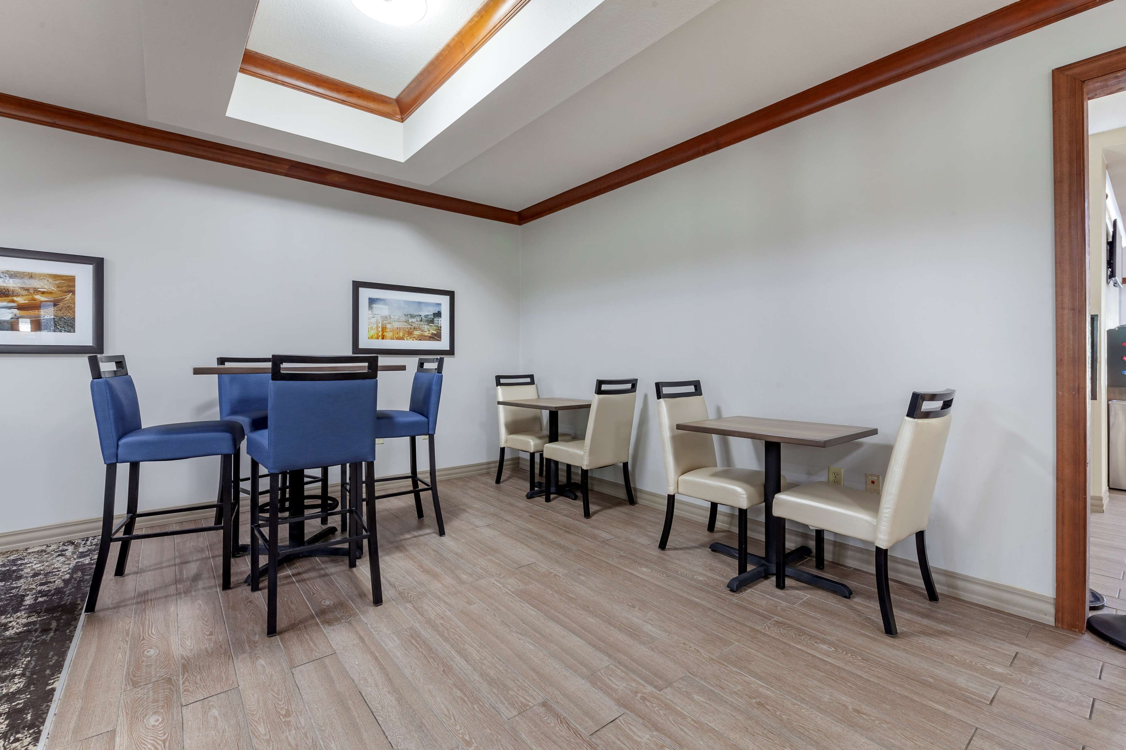 A dining area with a skylight, wooden beams, and a mix of blue and beige chairs.