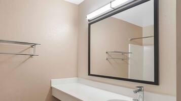 A bathroom with a white sink, a large mirror, and a towel rack.