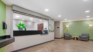 A reception area with a counter, a map on the wall, and two armchairs with a coffee table.