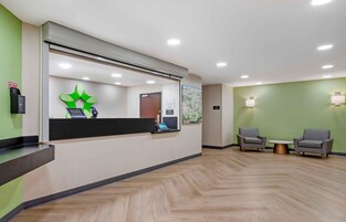 Un área de recepción con mostrador, un mapa en la pared y dos sillones con una mesita de centro.