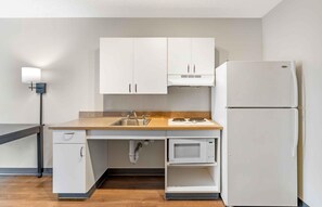 A compact kitchen with white cabinets, a microwave, a sink, and a refrigerator. - Extended Stay America Suites Tampa Airport Spruce Street (Tampa)