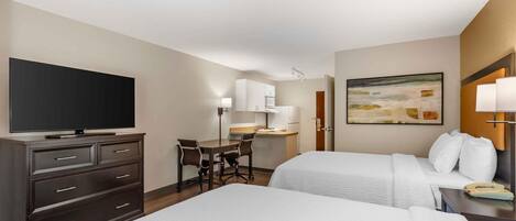 A hotel room with two beds, a desk, a TV, and a painting on the wall.