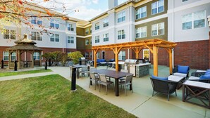 Un patio con mobiliario exterior, una parrilla y un pabellón.