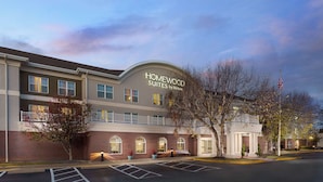 Un hotel con un letrero que dice "Homewood Suites by Hilton" y un estacionamiento enfrente.