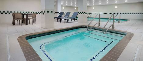 A swimming pool with a tiled deck, lounge chairs, and a dining area with tables and chairs.