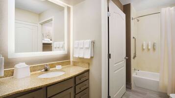A bathroom with a sink, mirror, towel rack, and a shower area.