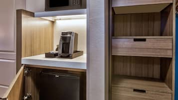 A kitchen with a built-in coffee maker, a microwave, and a refrigerator.