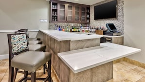 A bar area with a marble countertop, wooden cabinets, and a television mounted on the wall. - Hilton Garden Inn Minneapolis - Maple Grove (Maple Grove)