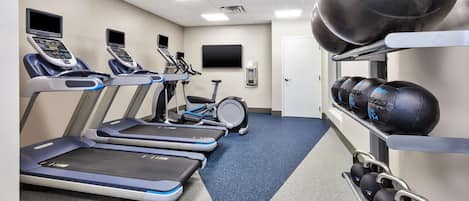 A gym with treadmills, a stationary bike, and weightlifting equipment.