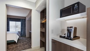 A hotel room with a bed, a kitchenette with a coffee maker, and a view of the outside. - Hilton Garden Inn Minneapolis - Maple Grove (Maple Grove)