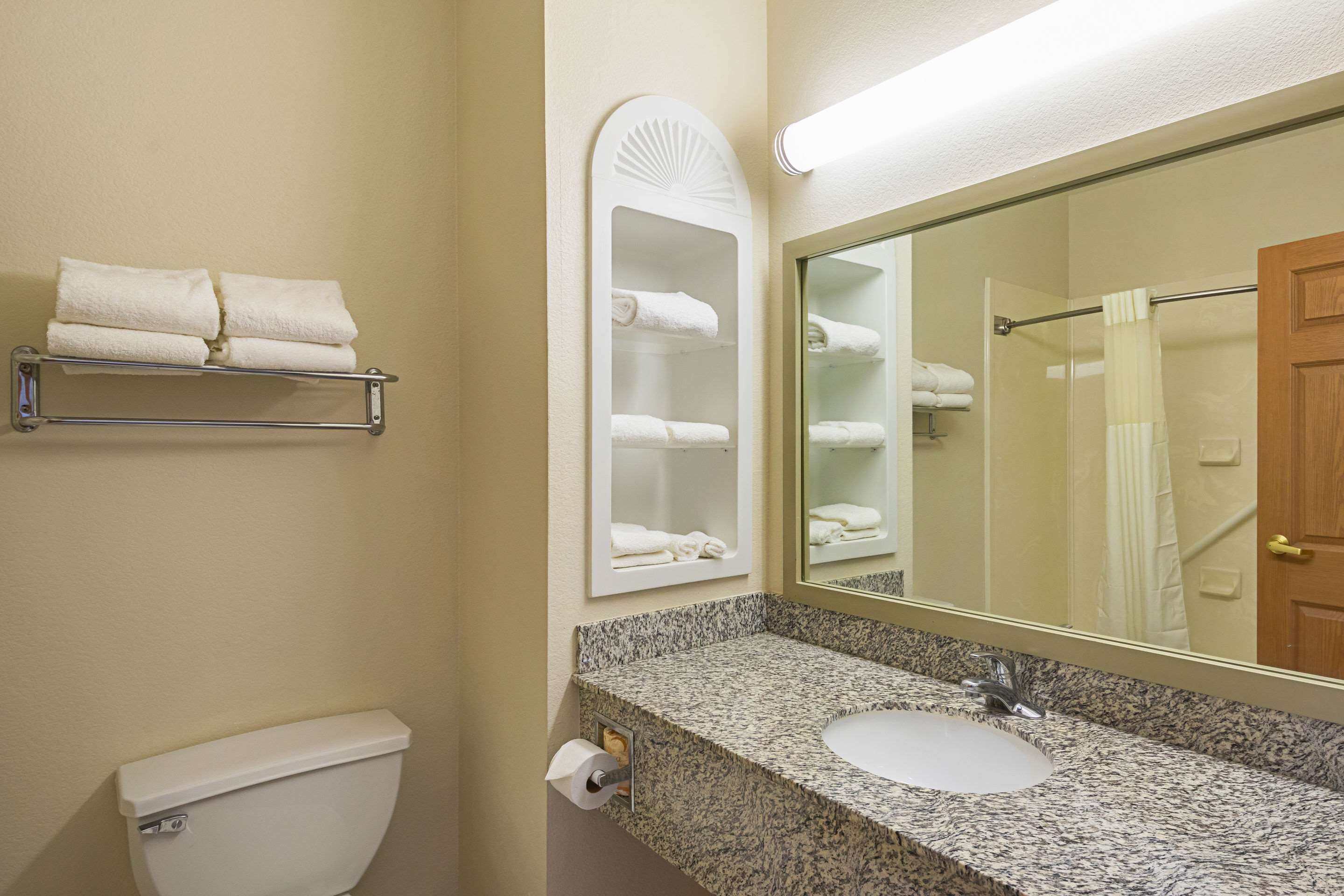 A bathroom with a toilet, sink, towel rack, and mirror.