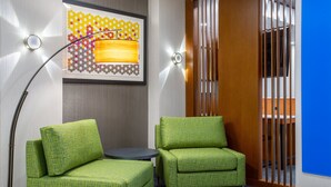 A modern room with two green upholstered chairs, a small round table, and a floor lamp. - Holiday Inn Express & Suites Fort Wayne by IHG (Fort Wayne)