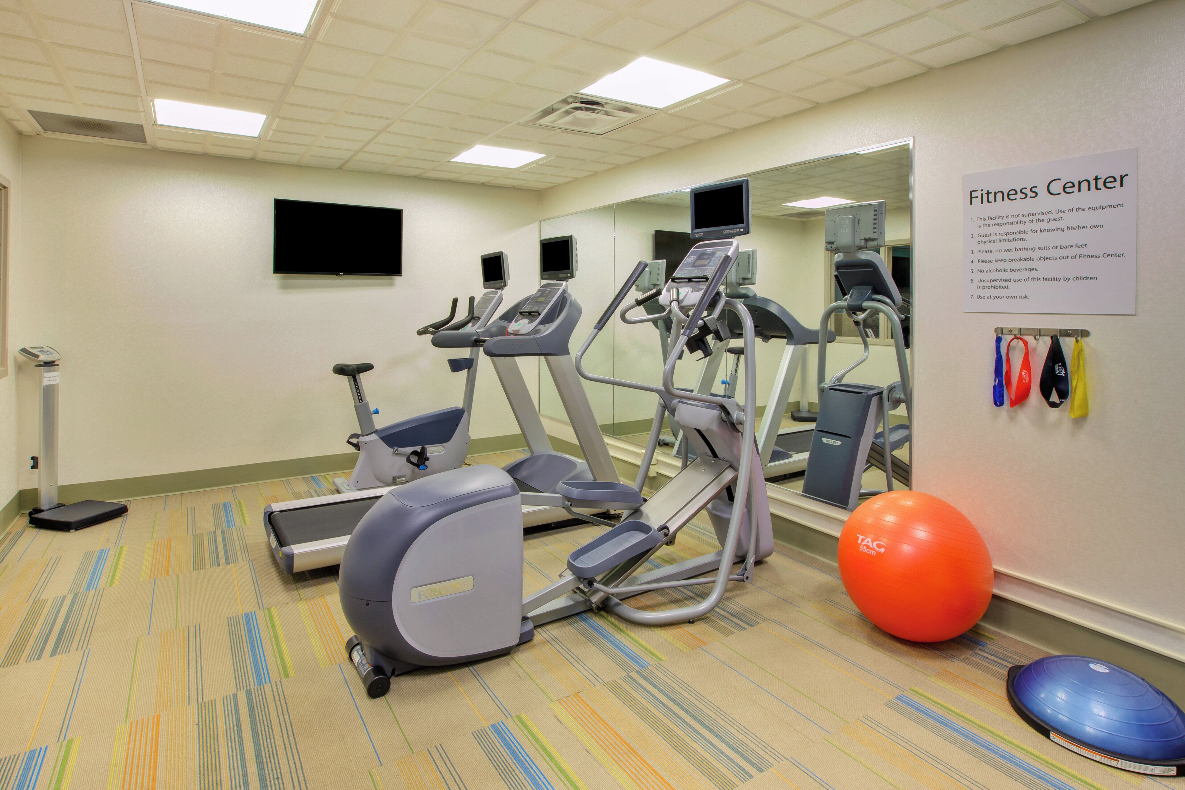 Un gimnasio equipado con cintas de correr, elípticas, bicicletas estáticas y pelotas de ejercicio.