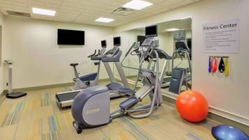 Un gimnasio equipado con cintas de correr, elípticas, bicicletas estáticas y pelotas de ejercicio.