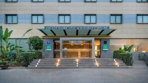 A hotel entrance with a modern facade, a staircase leading up to the entrance, and a sign indicating the hotel name and amenities. - AC Hotel Sevilla Fórum by Marriott (Seville)