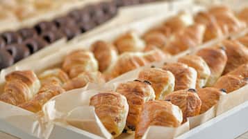 A tray of assorted pastries, including croissants and chocolate rolls, arranged on parchment paper.