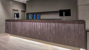 A modern reception area with a patterned counter, two monitors, and decorative blue vases. - AC Hotel Sevilla Fórum by Marriott (Seville)
