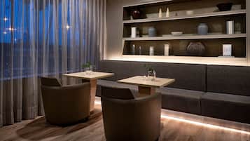 Een modern interieur met een bank, twee tafels en een plank met decoratieve objecten.