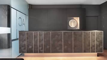 A reception desk with a geometric patterned design, a wall-mounted sign with the letters "OA", and a circular emblem above it.