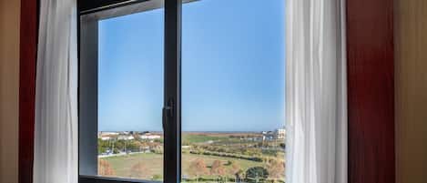Habitación con un ventanal grande, paneles de madera y vistas a un paisaje con edificios y árboles.