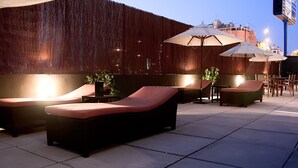 A rooftop lounge area with cushioned seating and umbrellas, featuring a wooden wall and cityscape views. - AC Hotel Murcia by Marriott (Murcia)