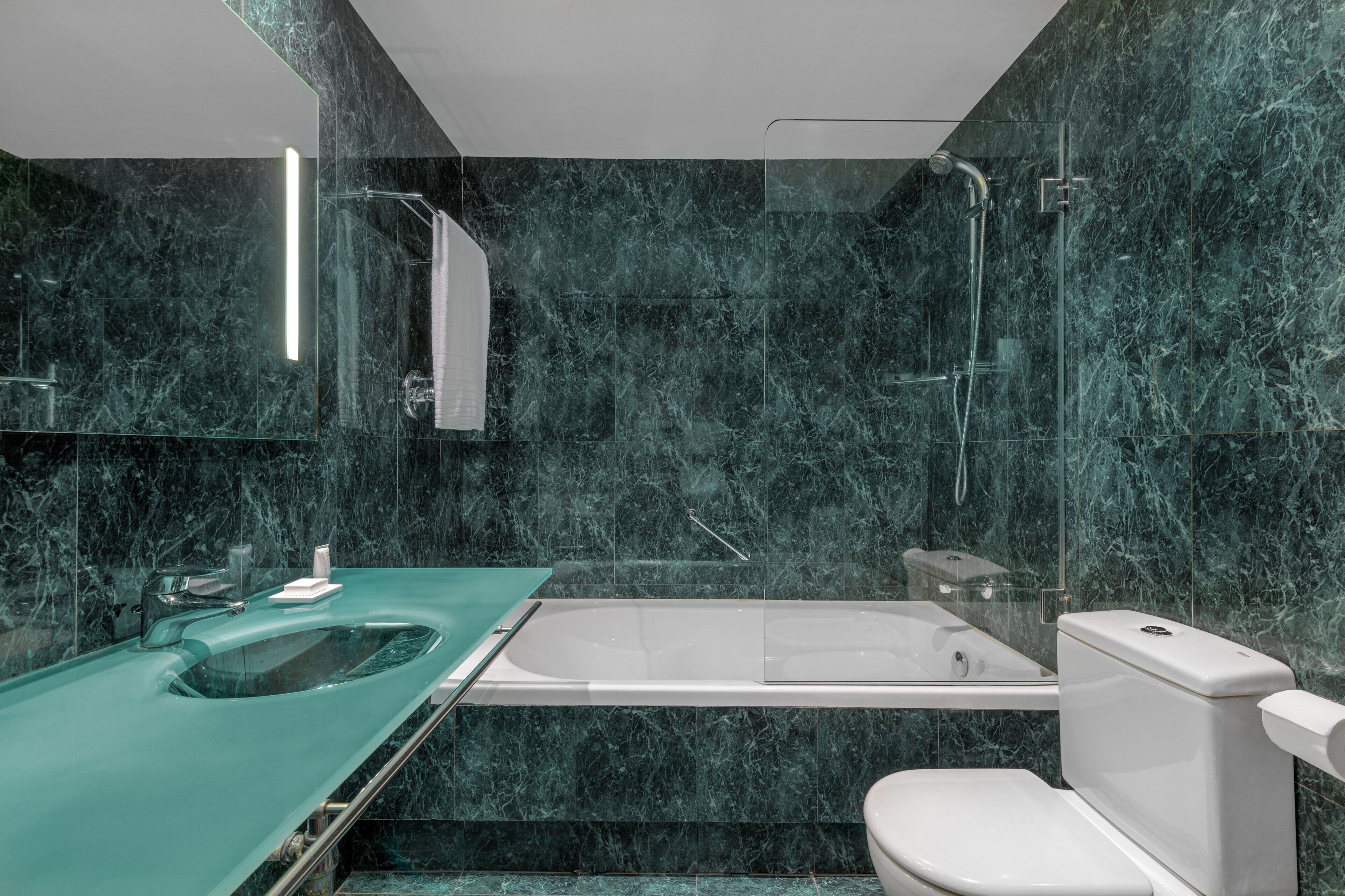 Et moderne badeværelse med håndvask i glas, badekar og toilet.