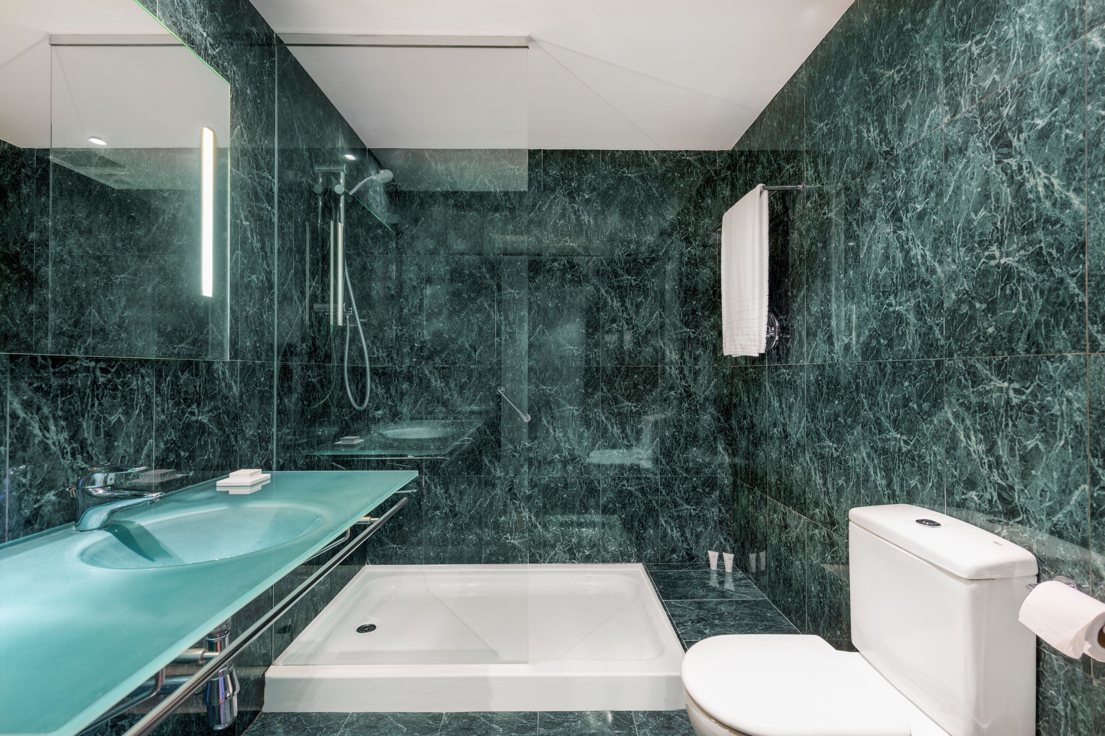 Un baño moderno con ducha acristalada, bañera independiente y un inodoro.