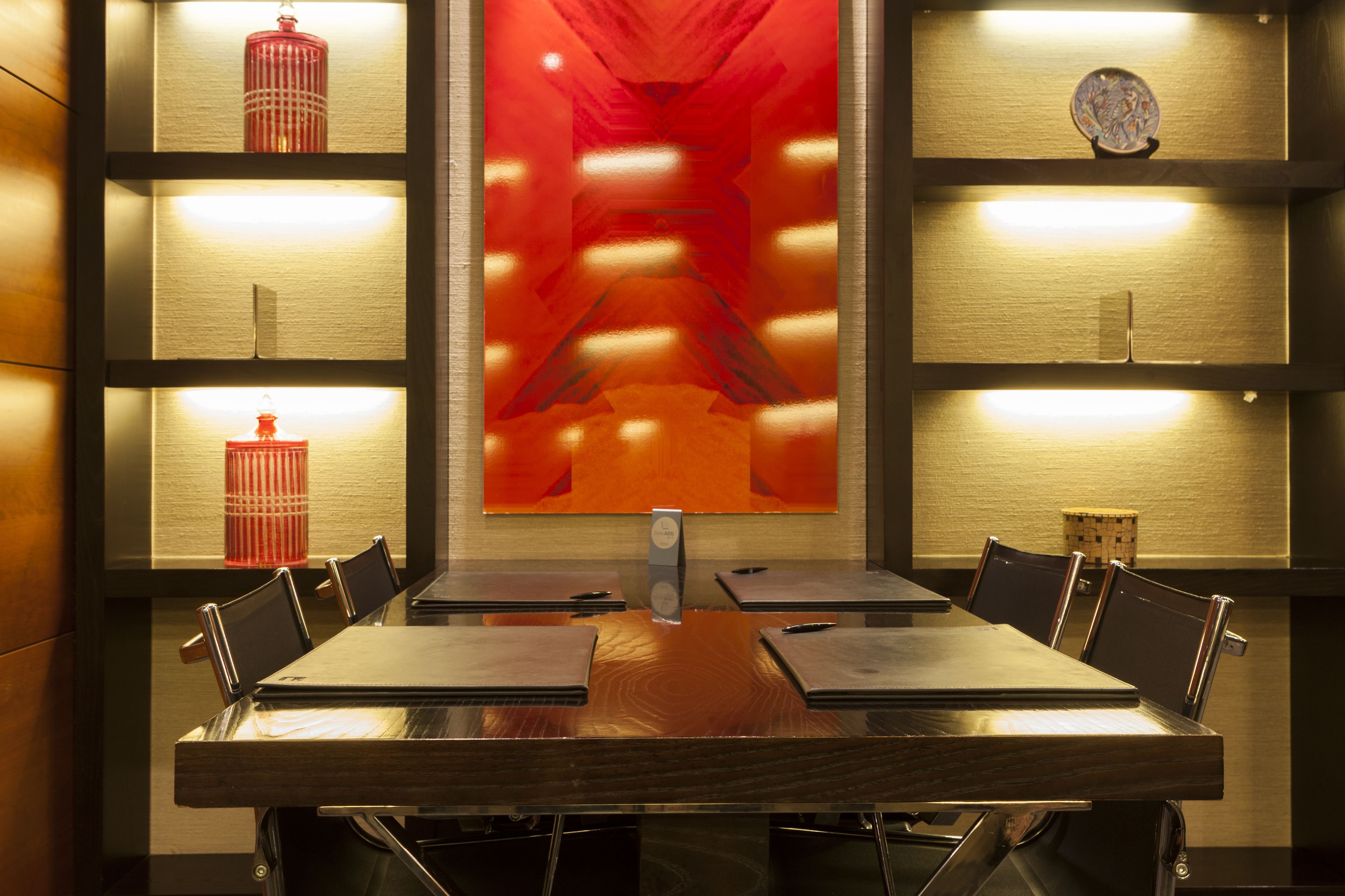 A conference room with a long table, chairs, and shelves with decorative items.