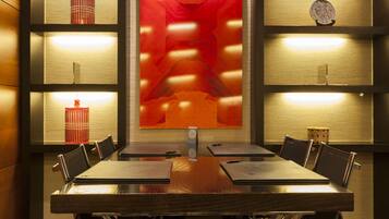 A conference room with a long table, chairs, and shelves with decorative items.