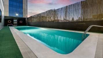 Una piscina al aire libre de temporada, sombrillas